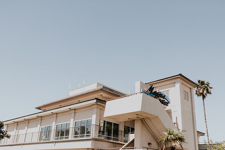 Exterior view of our corporate event venue, showcasing its modern architecture with spacious balconies and palm trees in the background